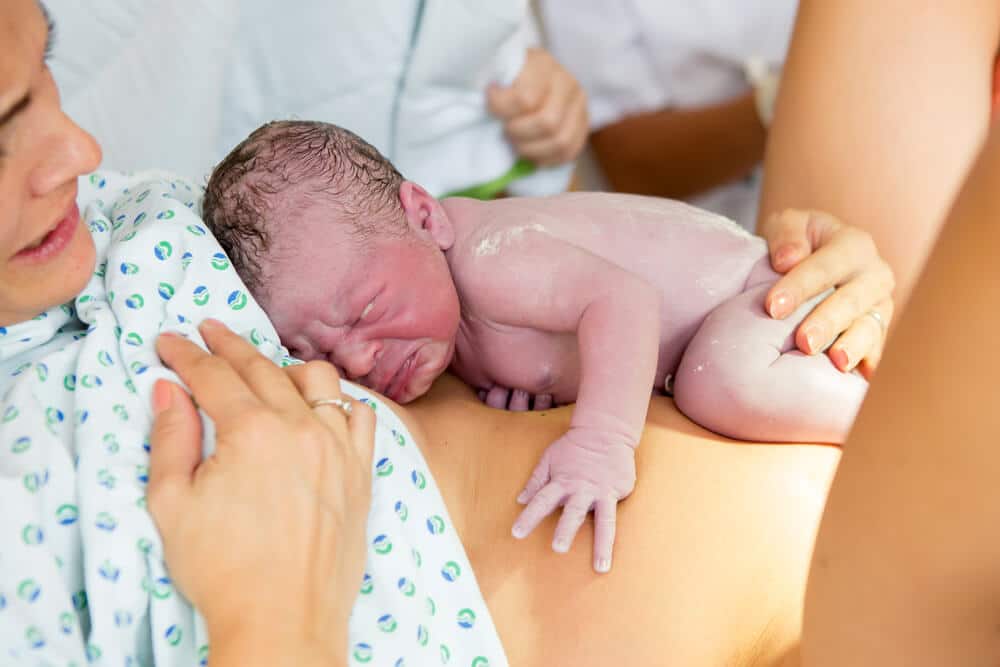 Hausgeburt - Neugeborenes liegt auf dem Bauch der Mutter