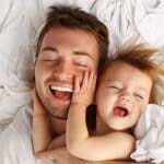 Vater werden - Papa kuschelt mit seinem Kind im Bett