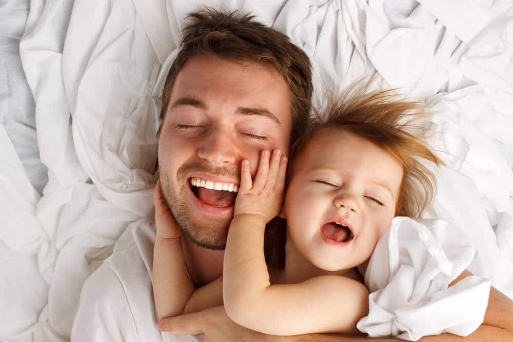 Vater werden - Papa kuschelt mit seinem Kind im Bett