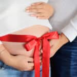 Schwangerschaft Rote Schleife um den Bauch einer Schwangeren