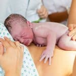 Hausgeburt - Neugeborenes liegt auf dem Bauch der Mutter