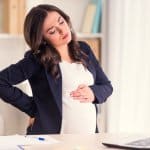 Schwangerschaftssymptome - Frau mit Laptop vor sich am Küchentisch