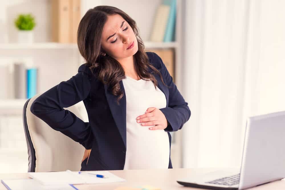 Schwangerschaftssymptome - Frau mit Laptop vor sich am Küchentisch