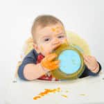 Beikosteinführung - Kleinkind mit schmutzigem Essensteller im Mund