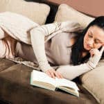 Die Nabel der Welt - Frau liegt lesend auf einer Couch