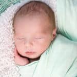 Pucken Ein Baby in einem grünen Tuch gepuckt