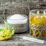 Hausmittel bei Erkältung Zuckerschale und Teetasse mit Kräutern und Fieberthermometer