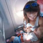 Flugreisen mit Baby - Mutter mit Baby im Arm in einem Flugzeug