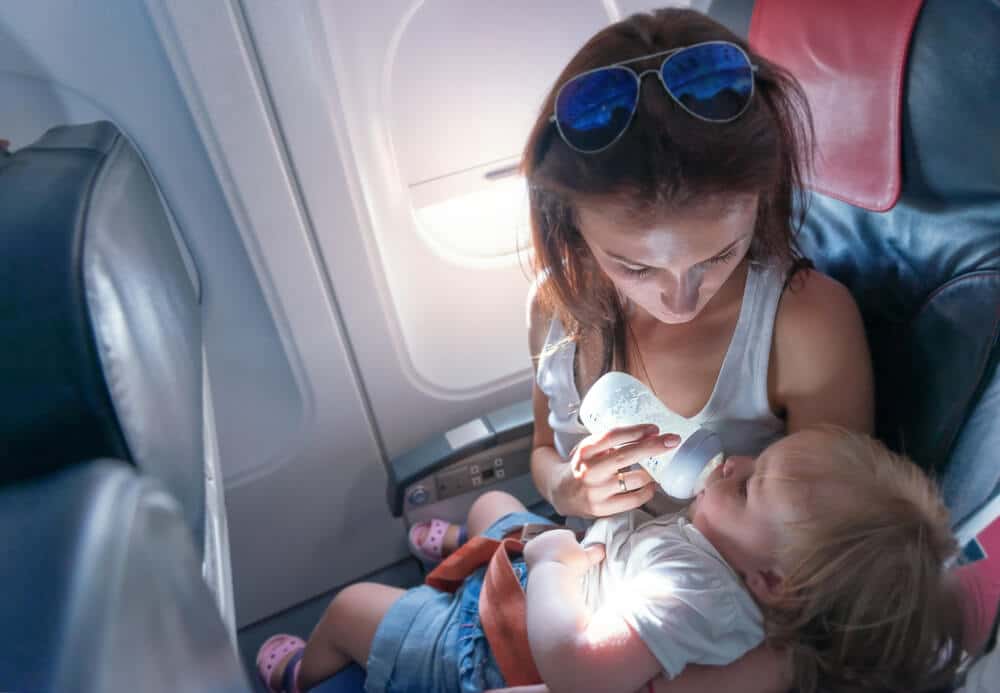 Flugreisen mit Baby - Mutter mit Baby im Arm in einem Flugzeug