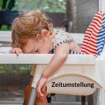 Zeitumstellung Kleinkind sitzt müde vornübergebeugt auf einem Kindersitz