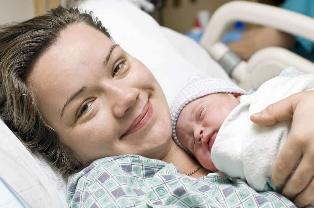 Wochenbett - Mutter mit Baby im Arm im Bett liegend