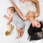 Wochenbett Mutter liegt mit Baby von einander abgewandt im Bett