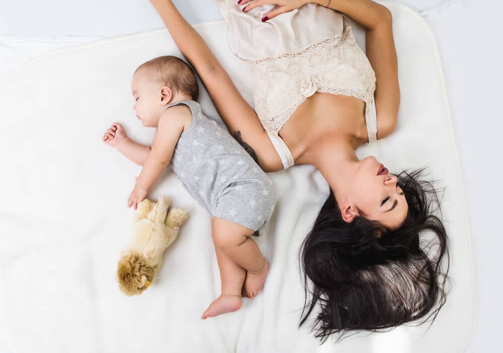 Wochenbett Mutter liegt mit Baby von einander abgewandt im Bett