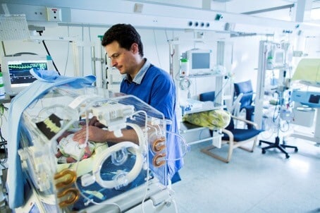 Frühchen - Arzt bei einer Untersuchung eines Frühchens im Brutkasten