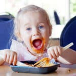 Mit Löffel essen Kleines Mädchen ist mit Messer und Gabel Nudeln