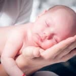 Kinderschlaf - Baby schläft auf den Händen seiner Mama