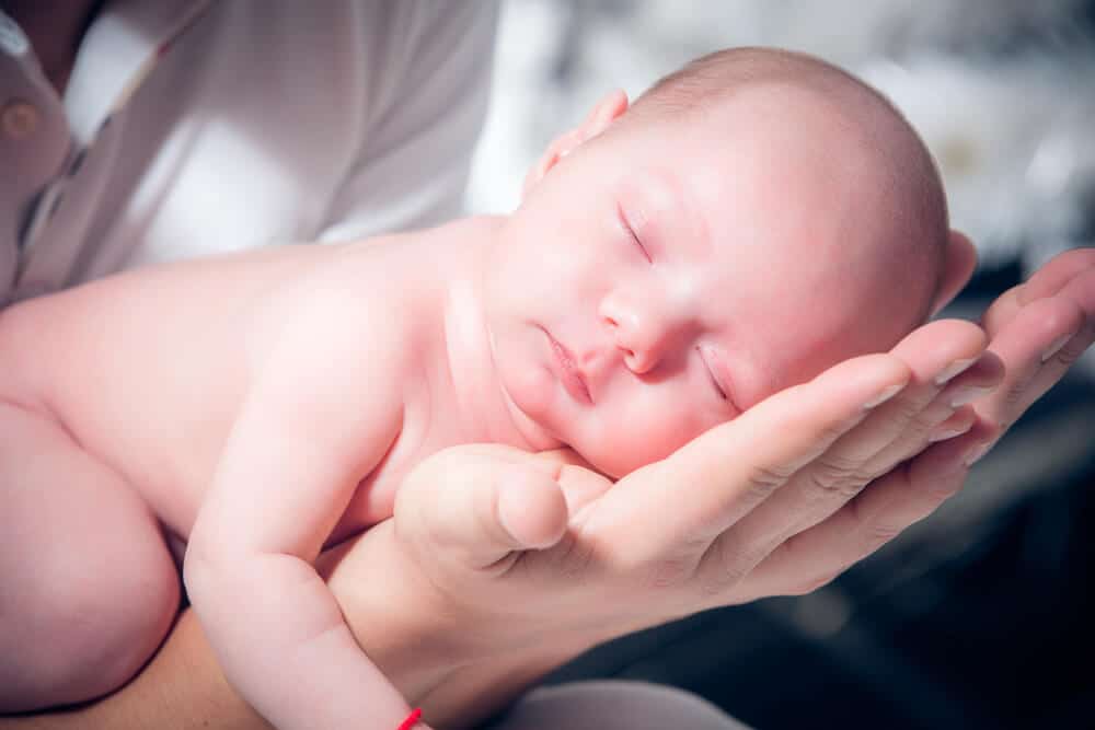 Kinderschlaf - Baby schläft auf den Händen seiner Mama