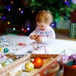 Nikolaus - Kleinkind spielt sitzend mit einem Weihnachtsgeschenk