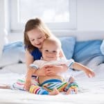 Geschwisterliebe - Große Schwester hält ihren kleinen Bruder im Arm