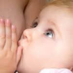 Stillen - ein Baby schaut seine Mutter beim Stillen mit großen Augen an