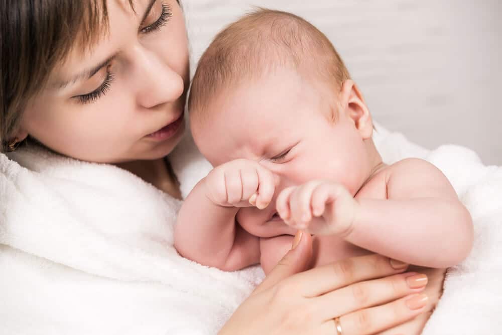 Babyschlaf - Baby wacht in den Armen seiner Mutter auf