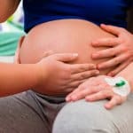 Doula tastet den Bauch einer Schwangeren