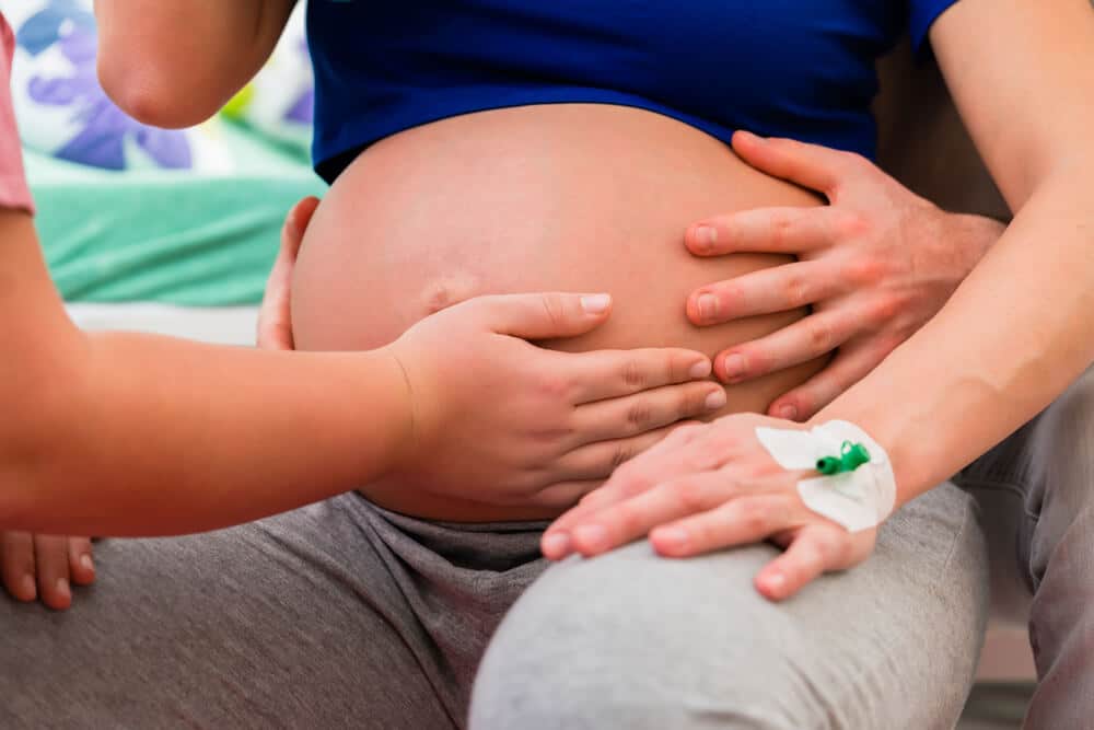 Doula tastet den Bauch einer Schwangeren